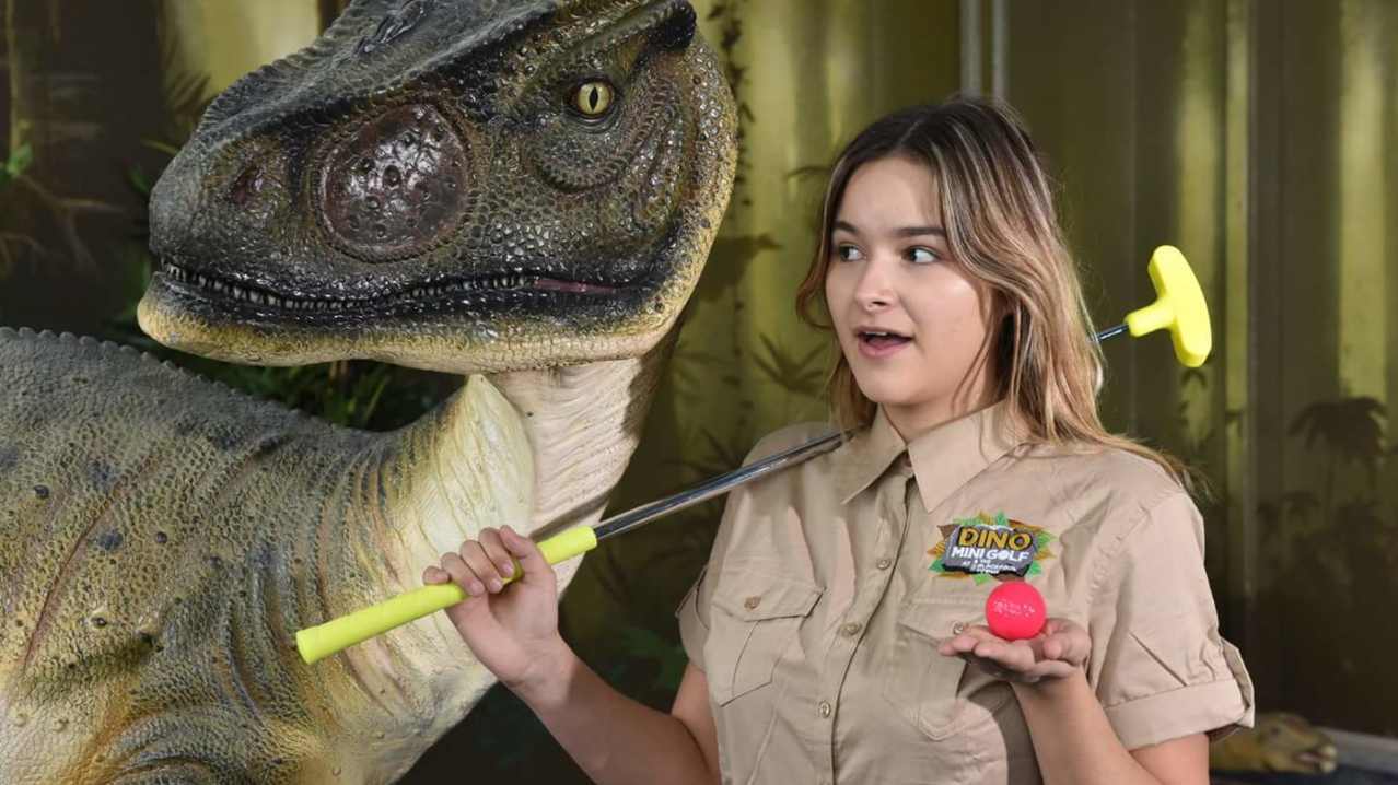 Staff member by dinosaur at Dino Golf in Blackpool