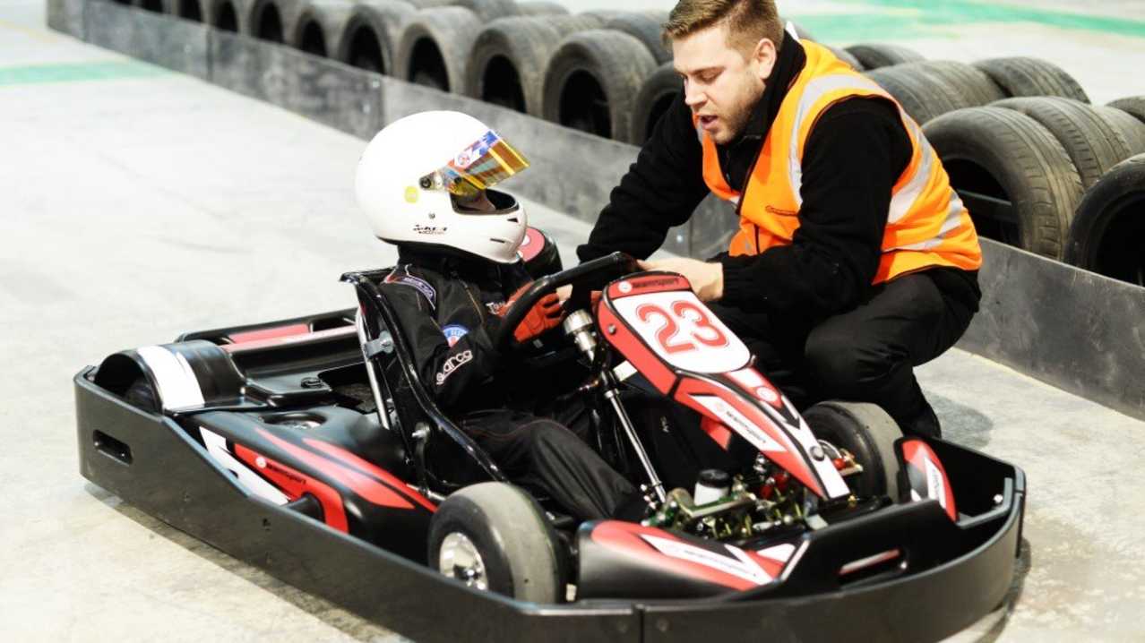 Someone helping a little boy in the kart at TeamSport Indoor Karting in Manchester Trafford Park