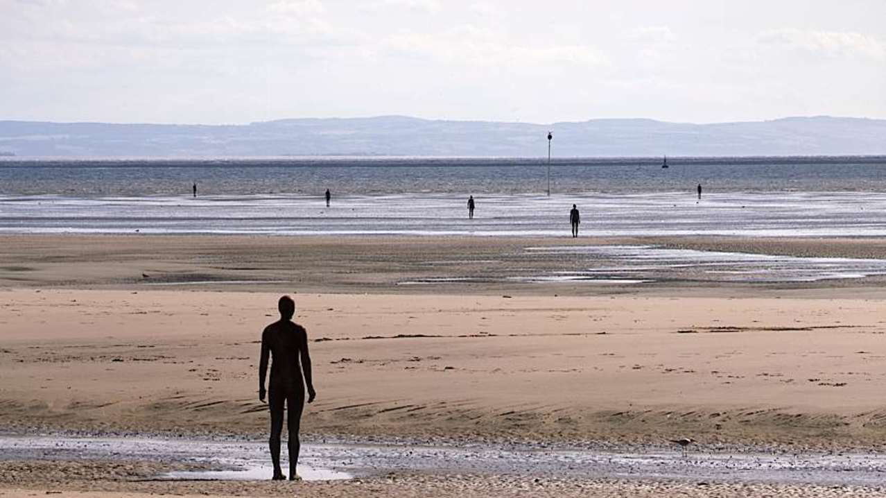 People on beach at Antony Gormleys Another Place in Liverpool People on beach at Antony Gormleys Another Place in Liverpool
