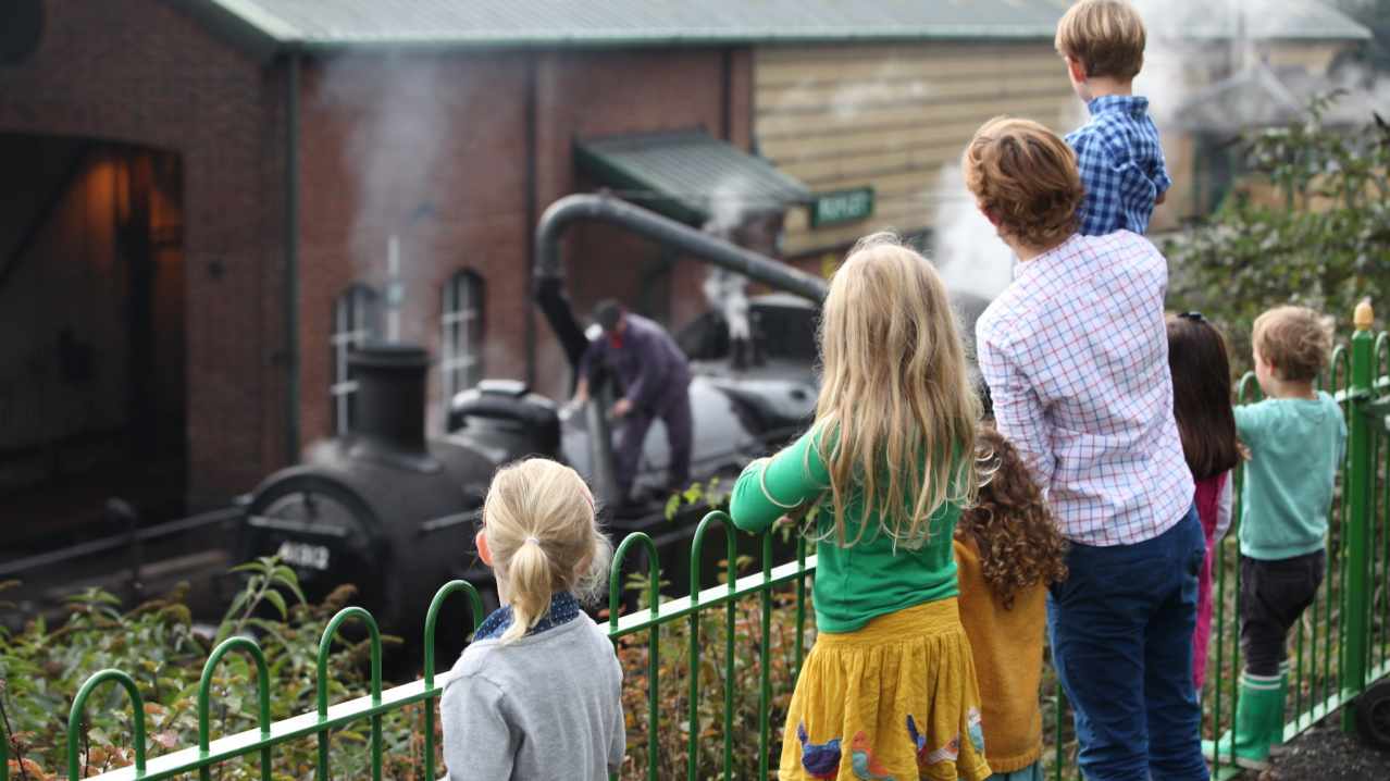 A family looks on at a steam train at Mid Hants Railway