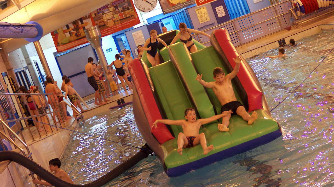 Kids on inflatable slide on swimming pool at Prudhoe Waterworld