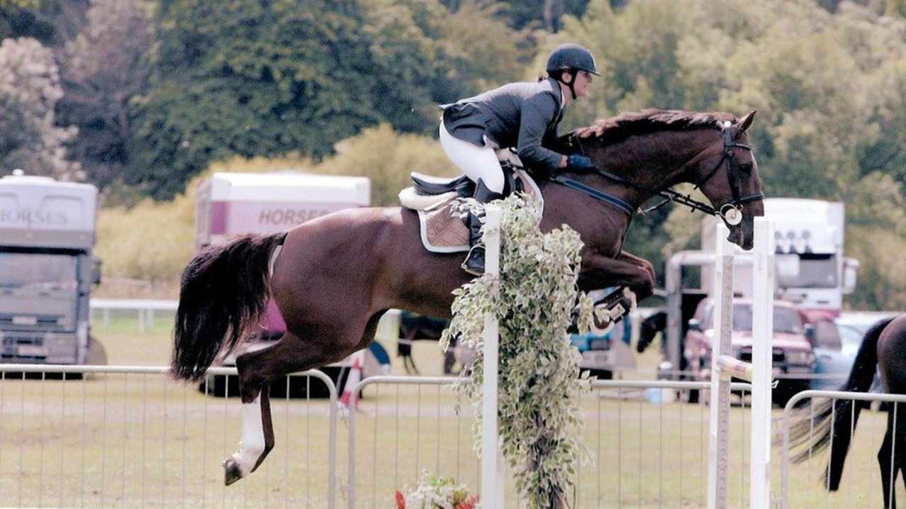 Horse and rider perform show-jump at Holly Tree Riding School in Plumley