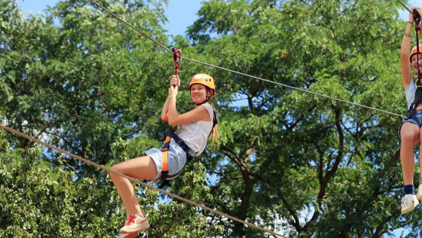person zooming on a zip line with trees in the background