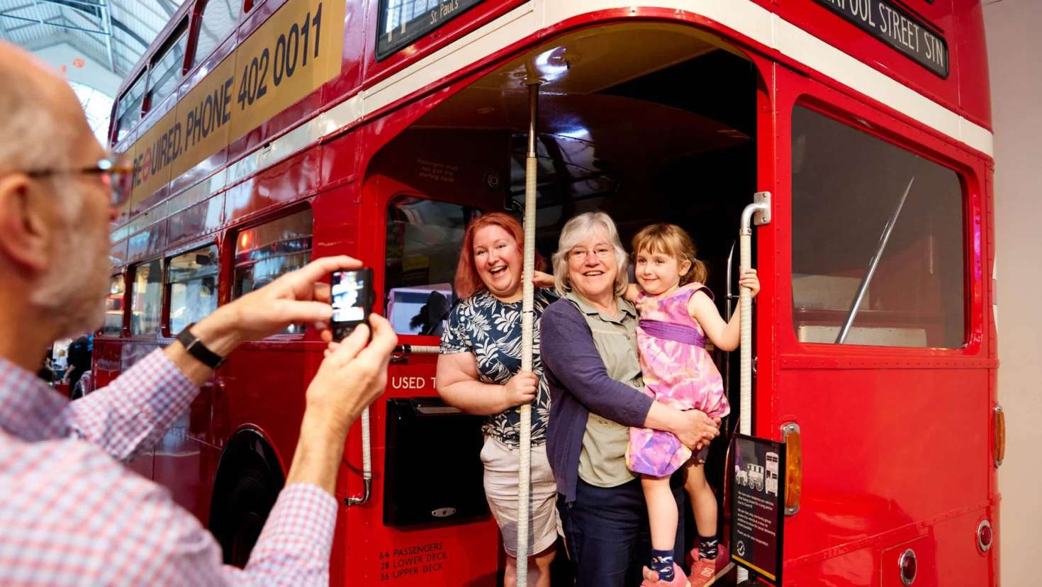 Family posing for a photo on board a classic red Routemaster bus at the London Transport Museum.