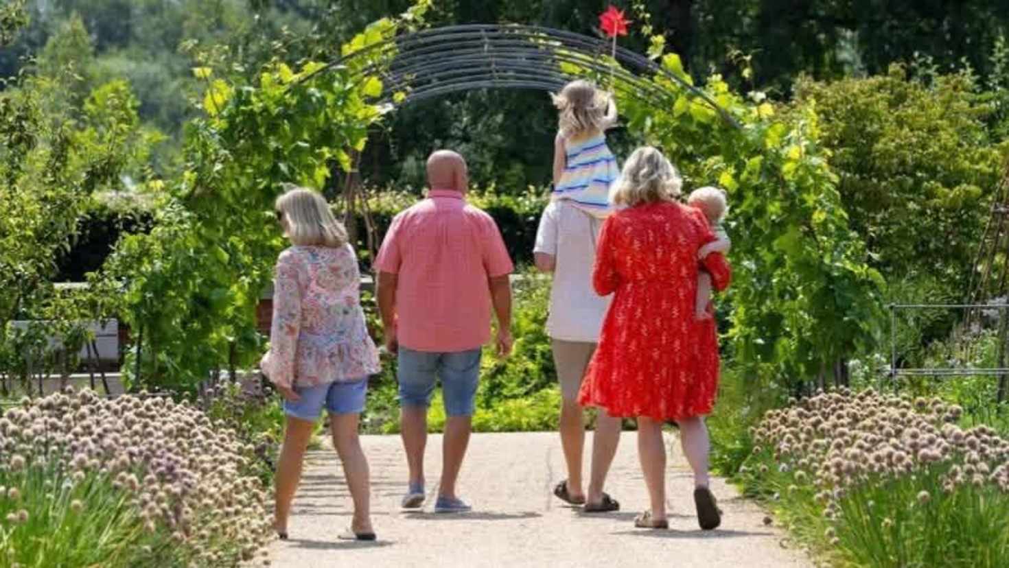 family walking through a garden blooming with flowers