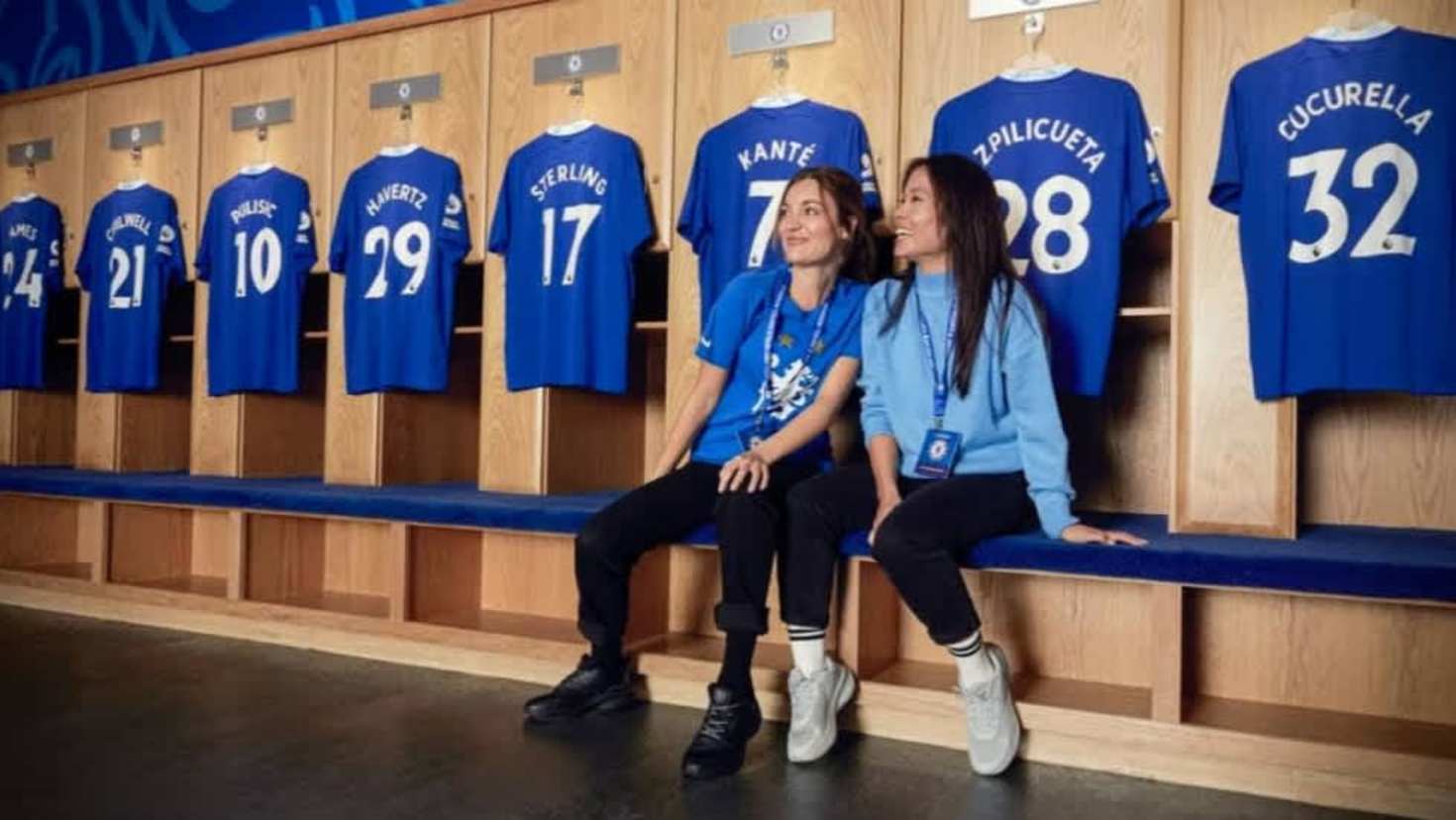 Visitors sitting in the Chelsea FC home dressing room alongside players’ shirts during the stadium tour