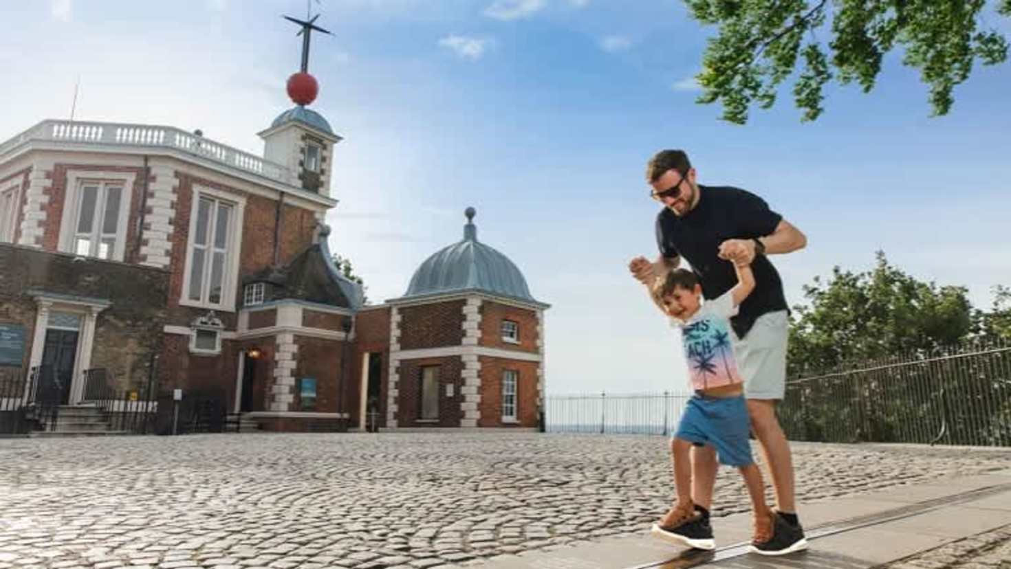 Father helping child balance on the Prime Meridian line at Royal Observatory Greenwich Father helping child balance on the Prime Meridian line at Royal Observatory Greenwich