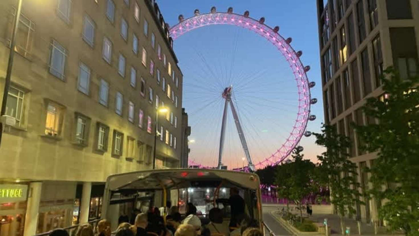 London Eye lit up at dusk, viewed from the upper deck of the Taylor Swift Singalong Bus Tour.