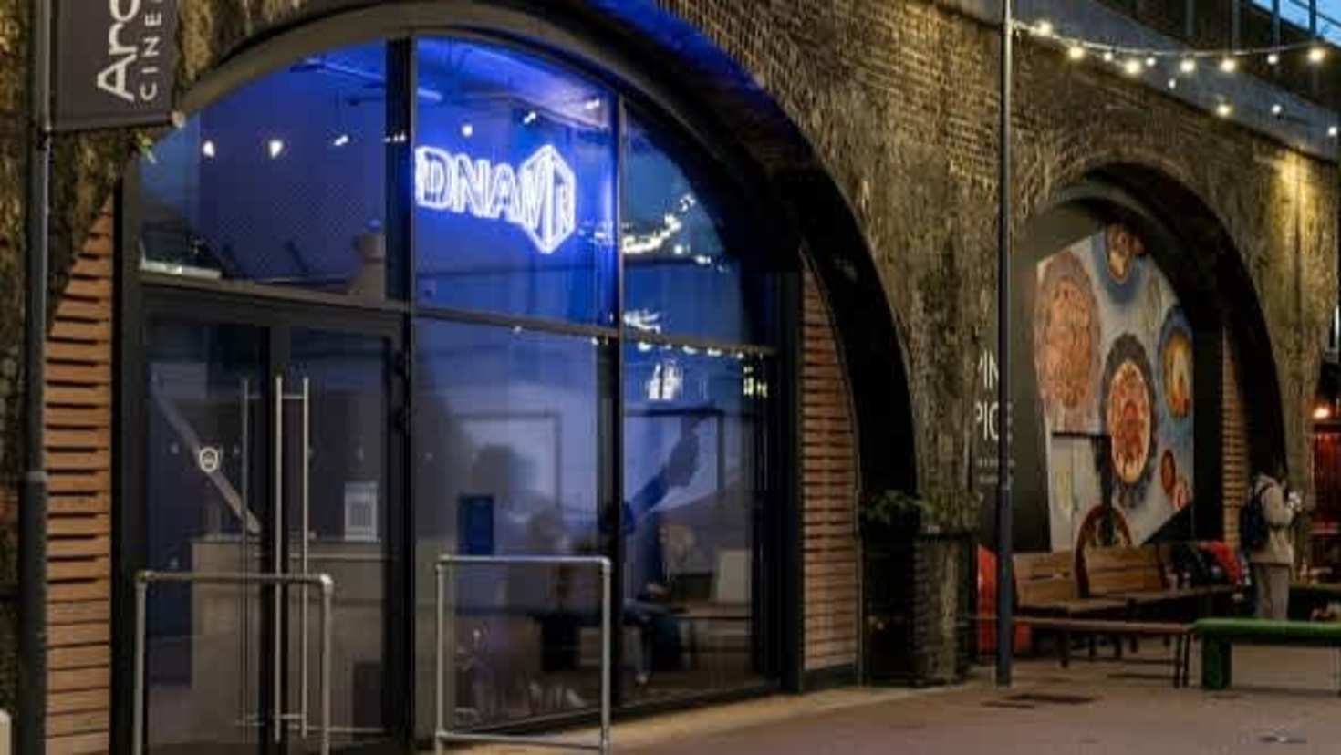 Exterior entrance of DNA VR Camden under railway arches with neon signage
