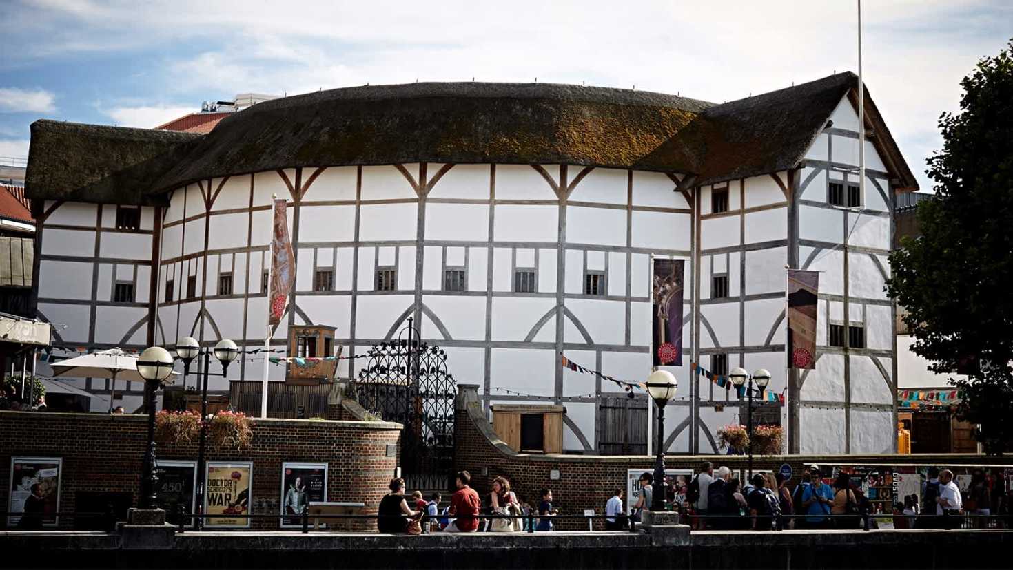 Exterior of Shakespeare’s Globe Theatre with thatched roof and riverside view.