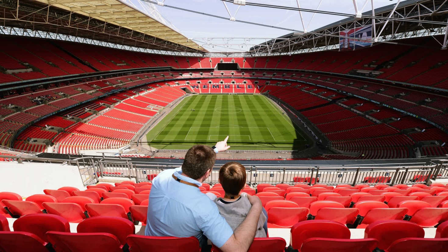 Father and son enjoying panoramic view of Wembley Stadium from the stands