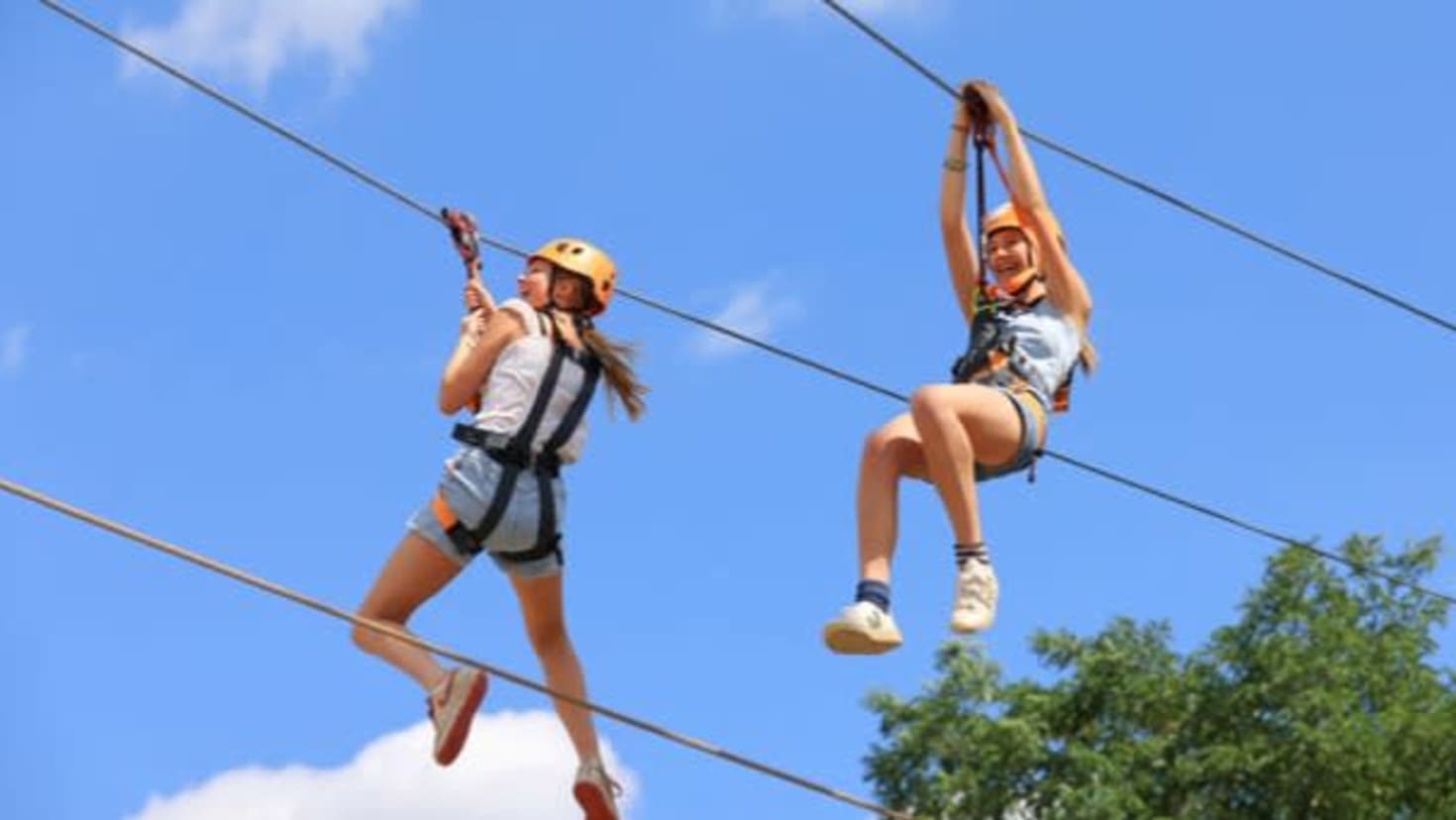 Two visitors riding the dual zipline at Gripped London adventure park in Hounslow