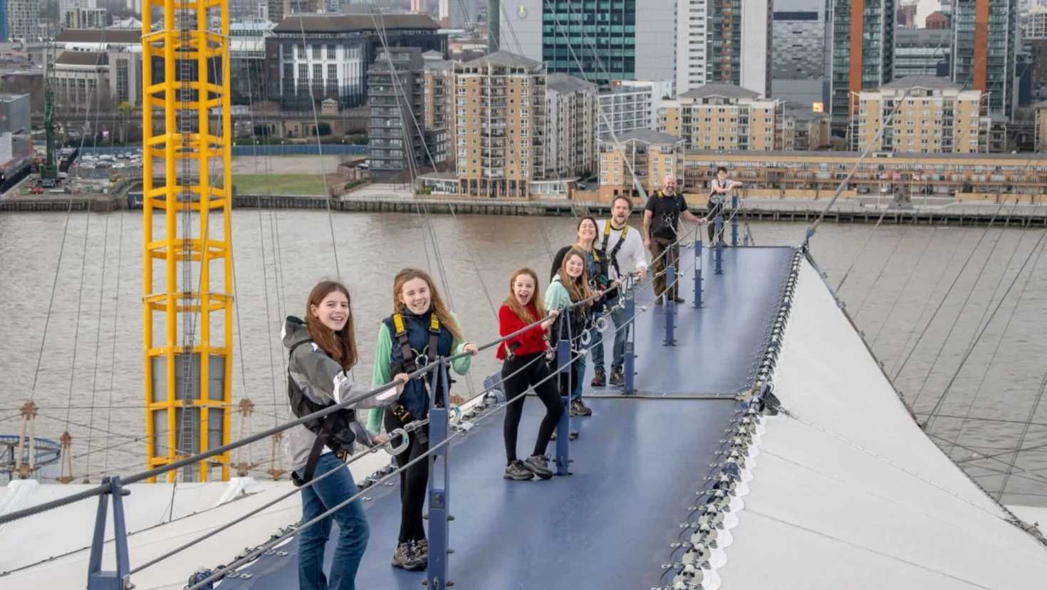 Group climbing the roof during an Up at The O2 London experience with views over Canary Wharf.