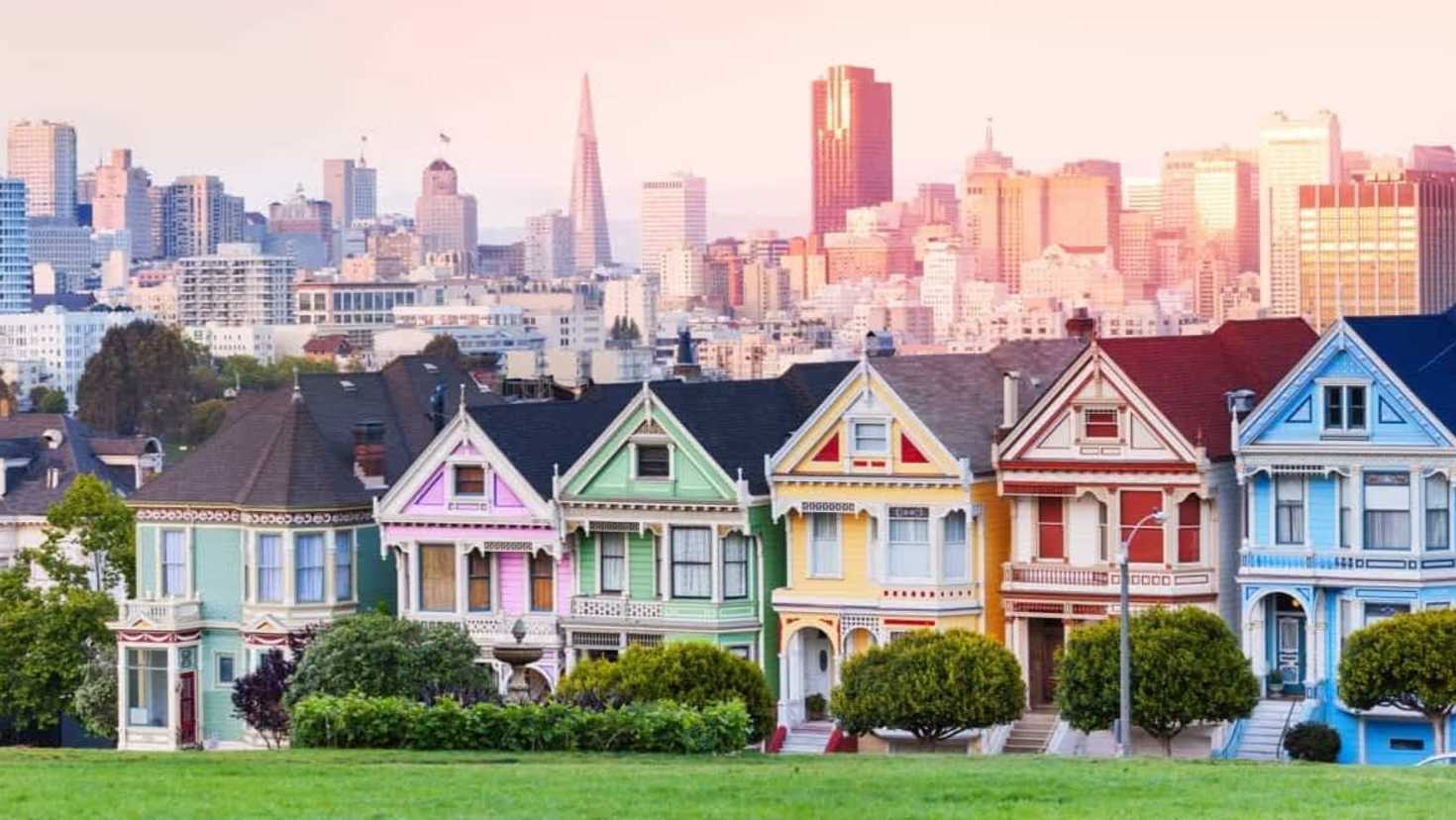 Row of colourful Victorian houses with city skyline behind Row of colourful Victorian houses with city skyline behind
