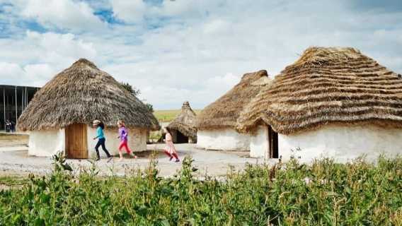 children running in front of the neolithic houses.