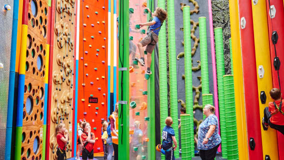 Children climbing colourful indoor walls at Rock Up Birmingham with unique vertical challenges.