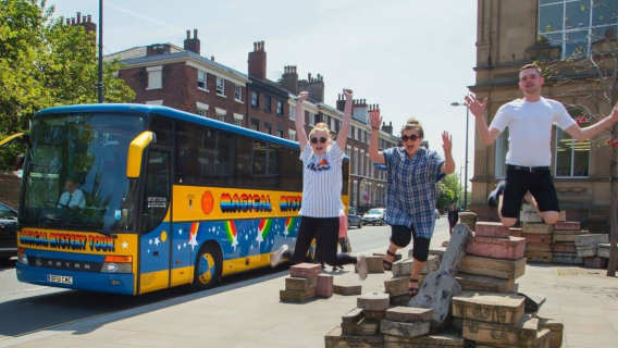 Group jumping for photos beside the Magical Mystery Tour bus in Liverpool city centre.