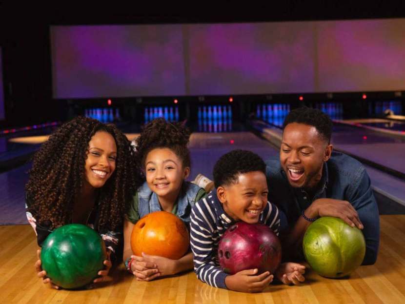 family holding bowling balls and smiling