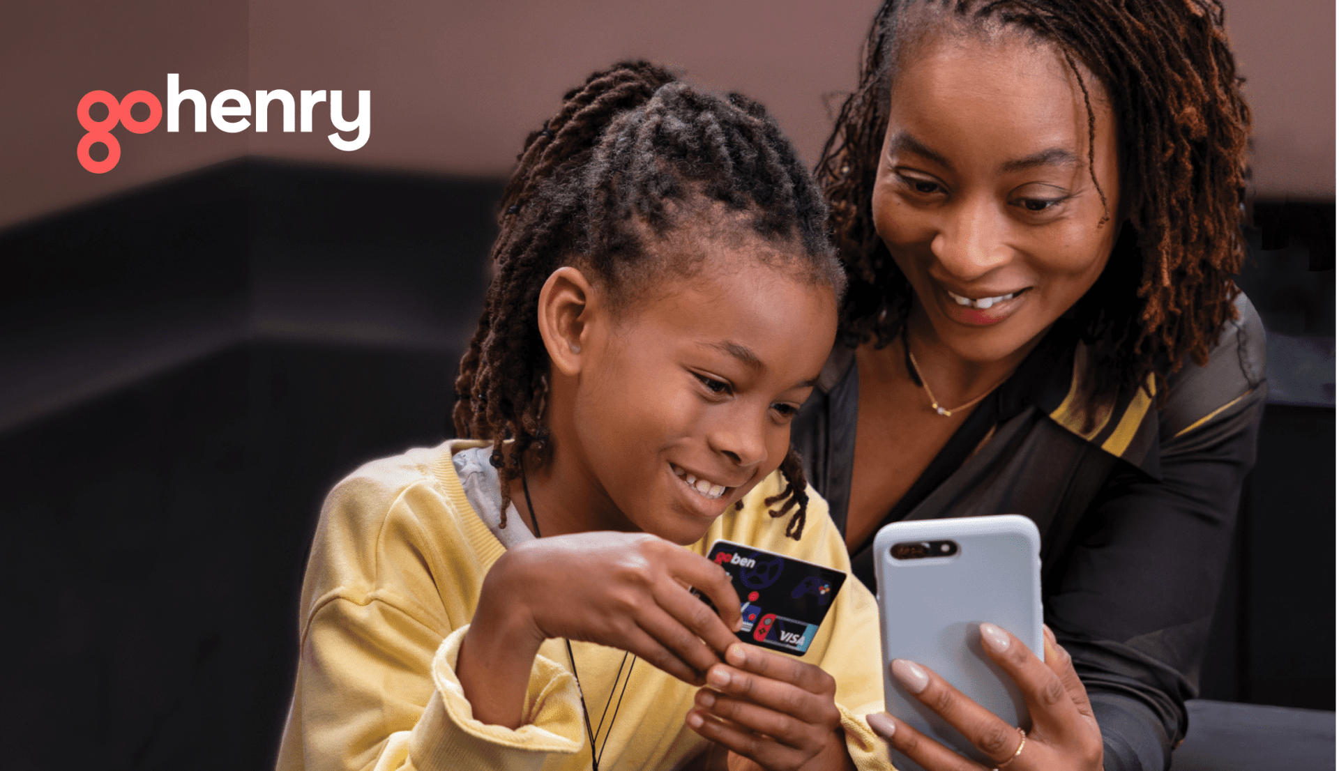 two people, one holding gohenry card, one looking at a phone