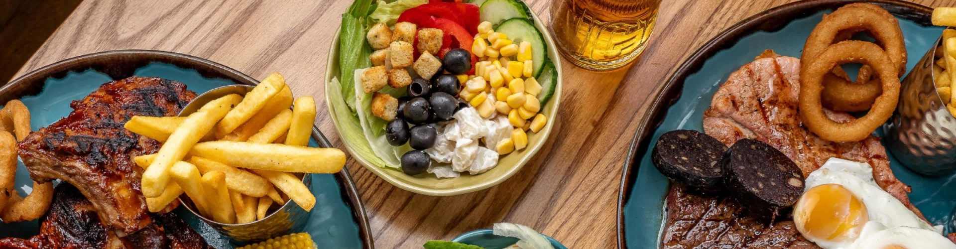 assortment of pub food, salad, grilled meat, chips and more