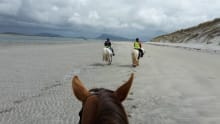 People riding horses on beach at Uist Community Riding School in the Isle of Benbecula