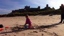 Girl making sand castles at Bamburgh Beach in Seahouses