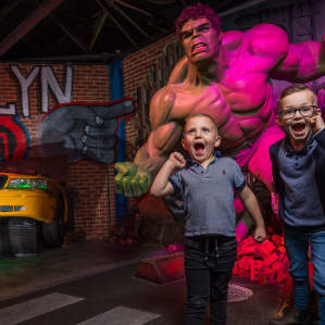 2 boys in front of a hulk wax figure posing like the hulk