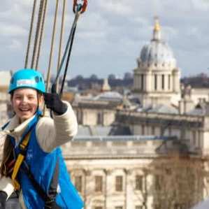 Smiling climber enjoying the Cutty Sark rig climb with views over the Old Royal Naval College in Greenwich