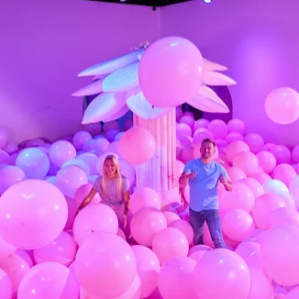 couple looking joyful within the giant pink ball pit