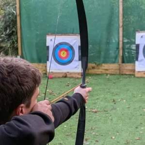 Participants aiming bows at archery targets outdoors