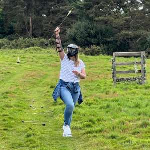 Participants aiming recurve bows at targets on an outdoor archery range