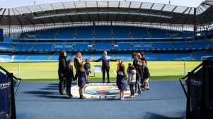 Tour group standing pitchside at Etihad Stadium during Manchester City Stadium Tour
