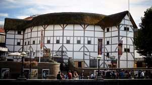 Exterior of Shakespeare’s Globe Theatre with thatched roof and riverside view.