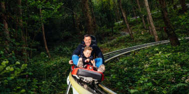 A dad and his son going down the Forest Coaster at Zip World Fforest