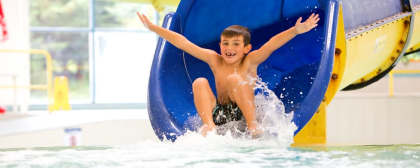boy sliding down a tube slide into a pool