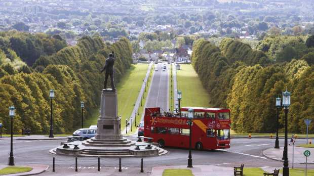 City Sightseeing Belfast Hop on Hop off Tour bus passes by statue of Lord Carson