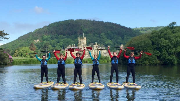 Young adults paddleboarding at Margam Park Adventure in Port Talbot