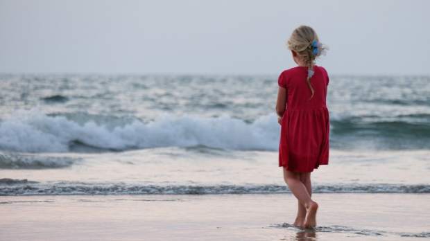 Girl standing on a sandy beach 