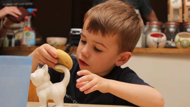 Boy washing pottery piece at Creative Biscuit Ceramics Cafe in South Woodford
