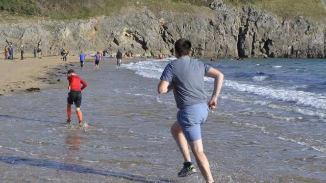 Boys running in ocean at Barafundle Bay in Stackpole