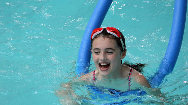 Girl swimming with foam roller at Hyde Leisure Pool in Hyde