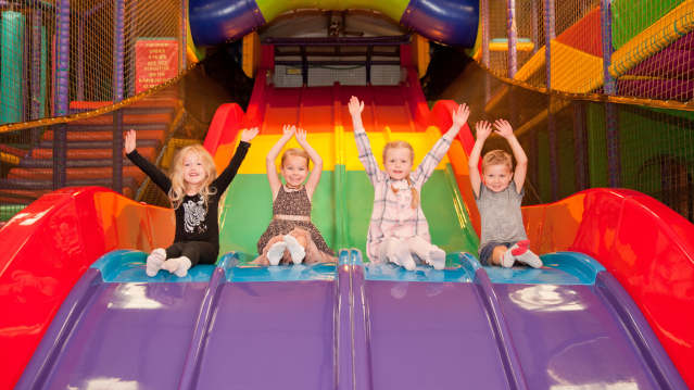 Four happy children sliding down a rainbow slide 