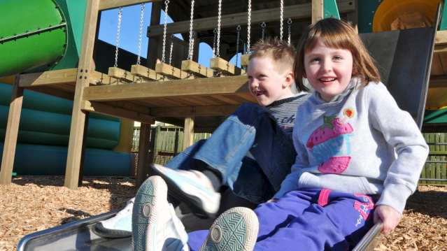 Kids on outdoor playground slide at Pili Palas Nature World in Anglesey