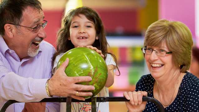 Grandparents with granddaughter bowling at Tenpin