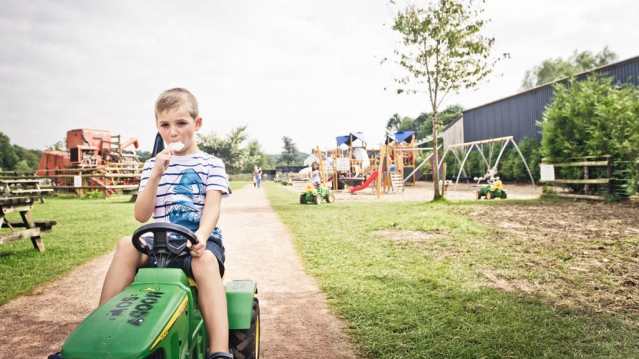 Boy on toy tractor with ice cream at Cefn Mably Farm Park in Cardiff
