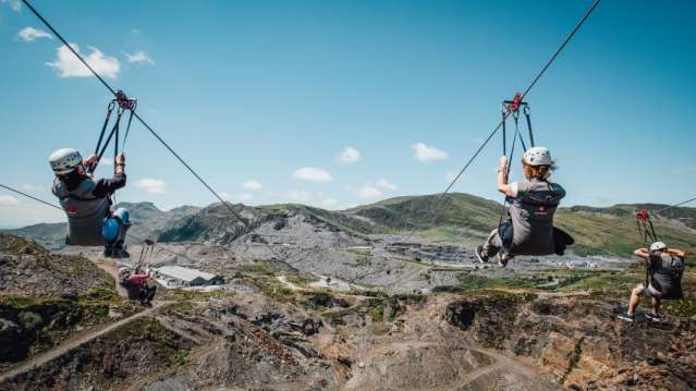 Four people going down a zip wire at Zip World Slate Caverns in Gwynedd