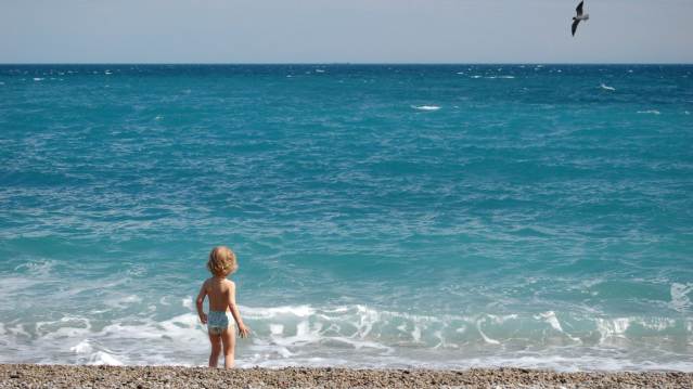 Toddler on a pebble beach playing by the water