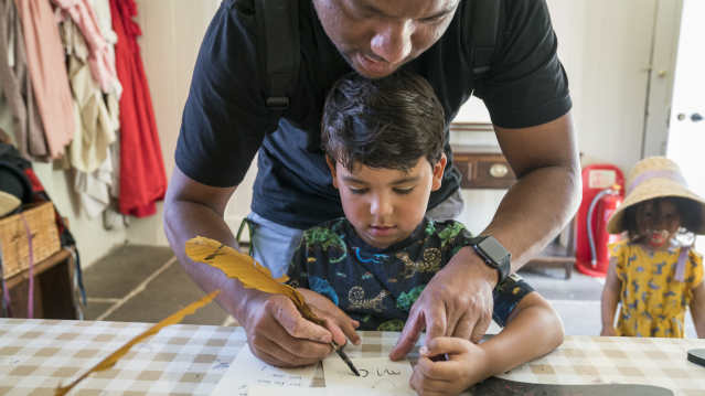 A man and a little boy writing with a quill at Jane Austen's House in Hampshire