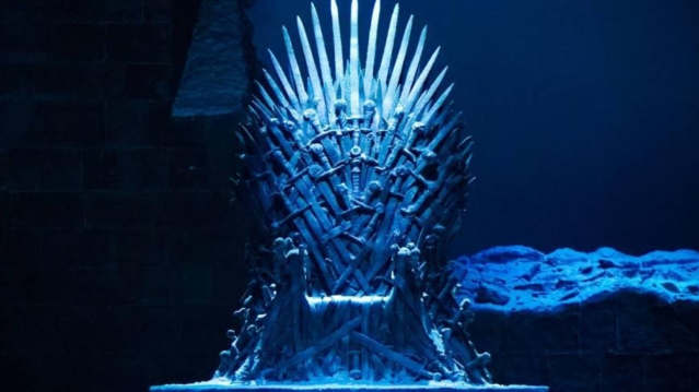 The iconic Iron Throne surrounded by dramatic blue lighting, part of the Game of Thrones Studio Tour photo opportunities.