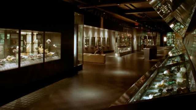 Darkly lit Mineral Gallery at the Natural History Museum featuring crystal and gemstone displays in glass cases.
